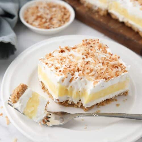 Slice of coconut delight on a plate with a forkful taken out.
