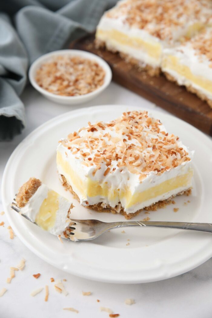 Slice of coconut delight on a plate with a forkful taken out.