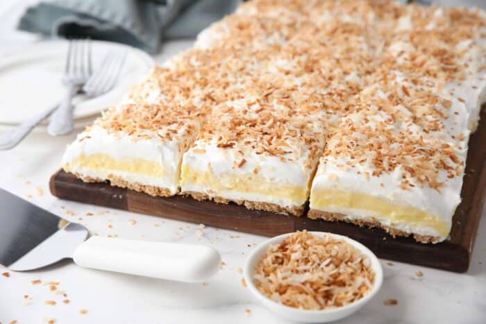 Coconut delight with layers of graham cracker crust, cream cheese, coconut pudding, whipped topping, and toasted coconut.