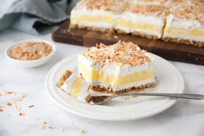 Slice of coconut lush on a plate with a forkful taken out.