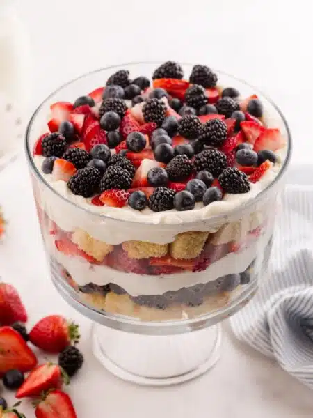 Red white and blue trifle in a clear trifle bowl showing layers of pound cake, whipped cream cheese, and berries.