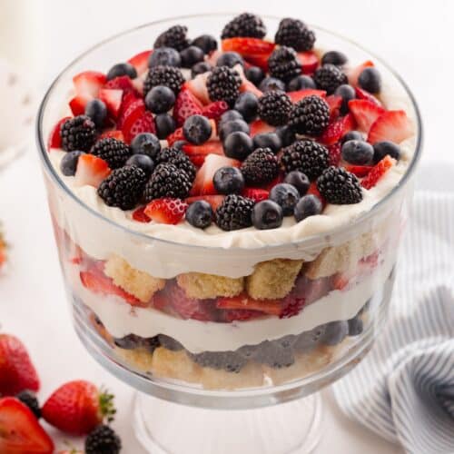Red white and blue trifle in a clear trifle bowl showing layers of pound cake, whipped cream cheese, and berries.