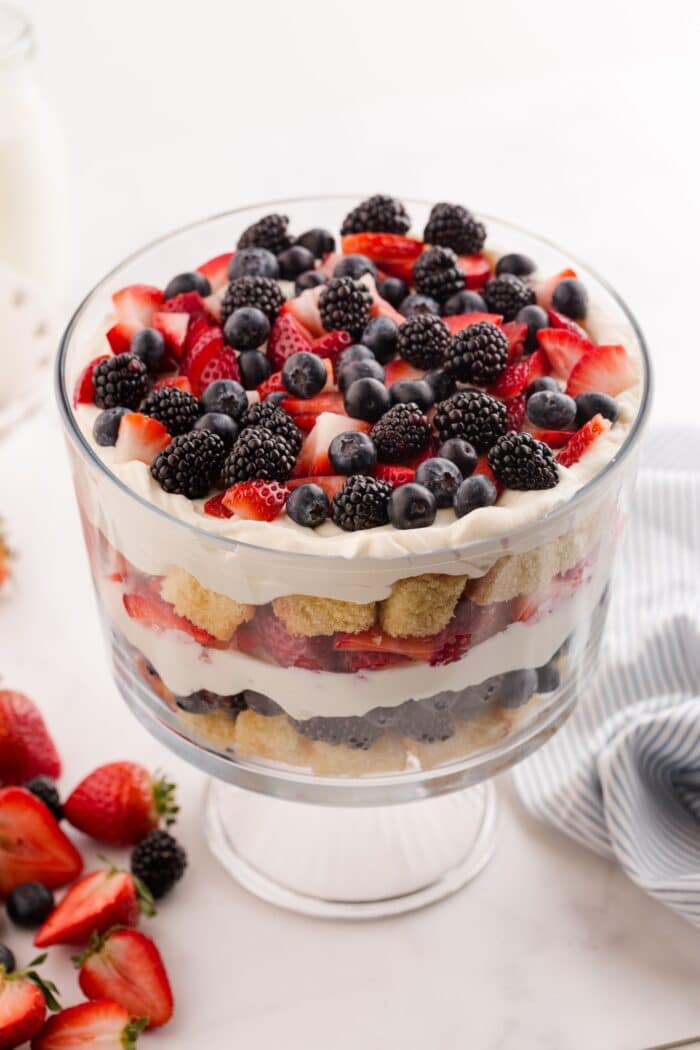 Red white and blue trifle in a clear trifle bowl showing layers of pound cake, whipped cream cheese, and berries.