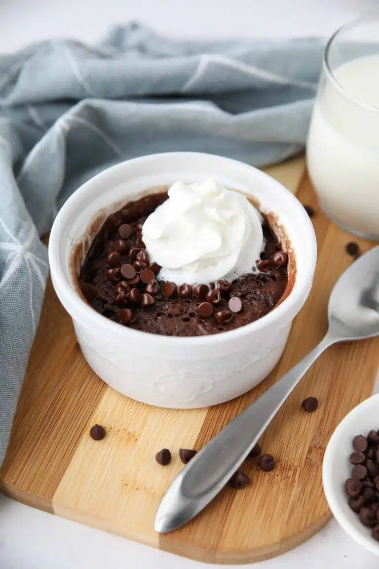 Microwave chocolate cake in a ramekin with mini chocolate chips and whipped cream on top.