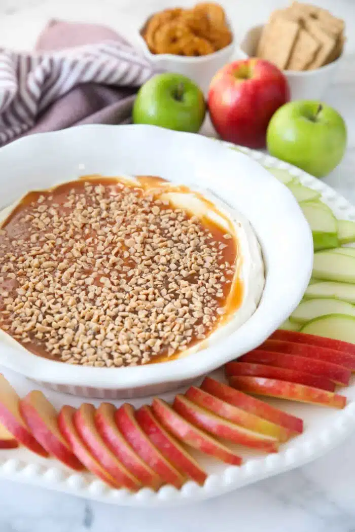 Caramel Apple Dip in a bowl with sliced apples on the side.