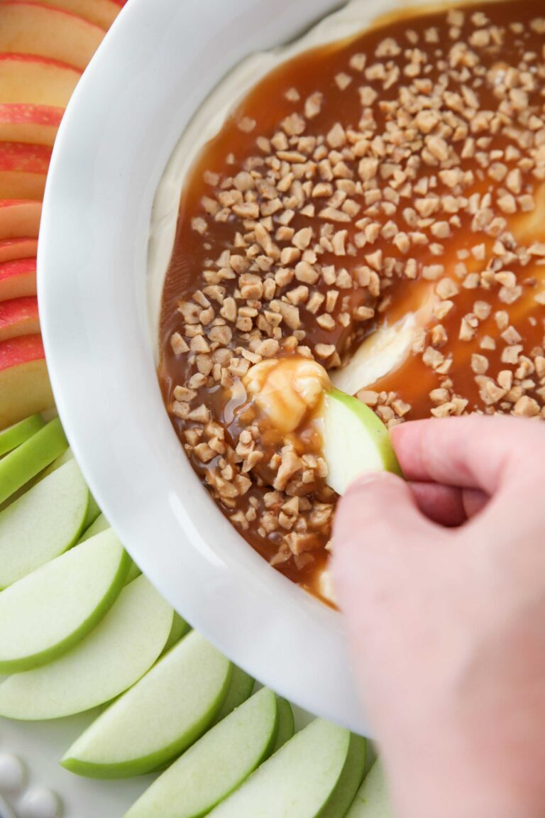 Close up of an apple scooping up cream cheese caramel apple dip.