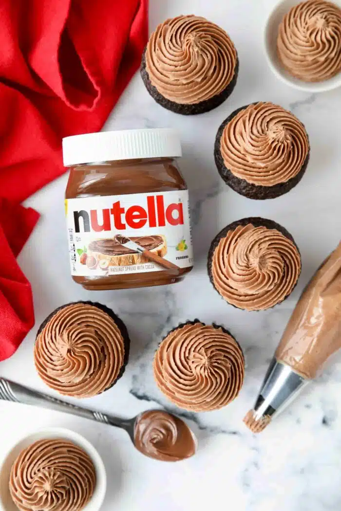 Jar of Nutella next to piped frosting on top cupcakes.