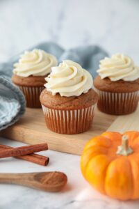 Side view of pumpkin cupcakes with cream cheese frosting piped on top.