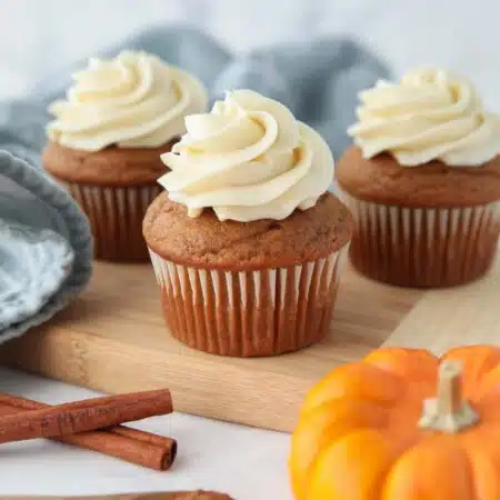 Side view of pumpkin cupcakes with cream cheese frosting piped on top.