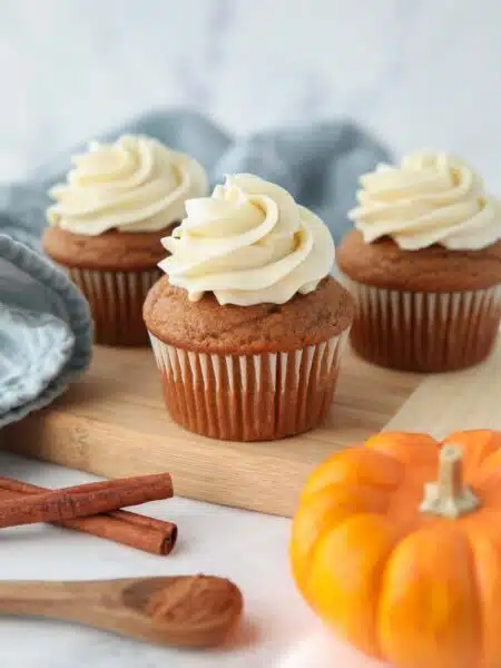 Side view of pumpkin cupcakes with cream cheese frosting piped on top.
