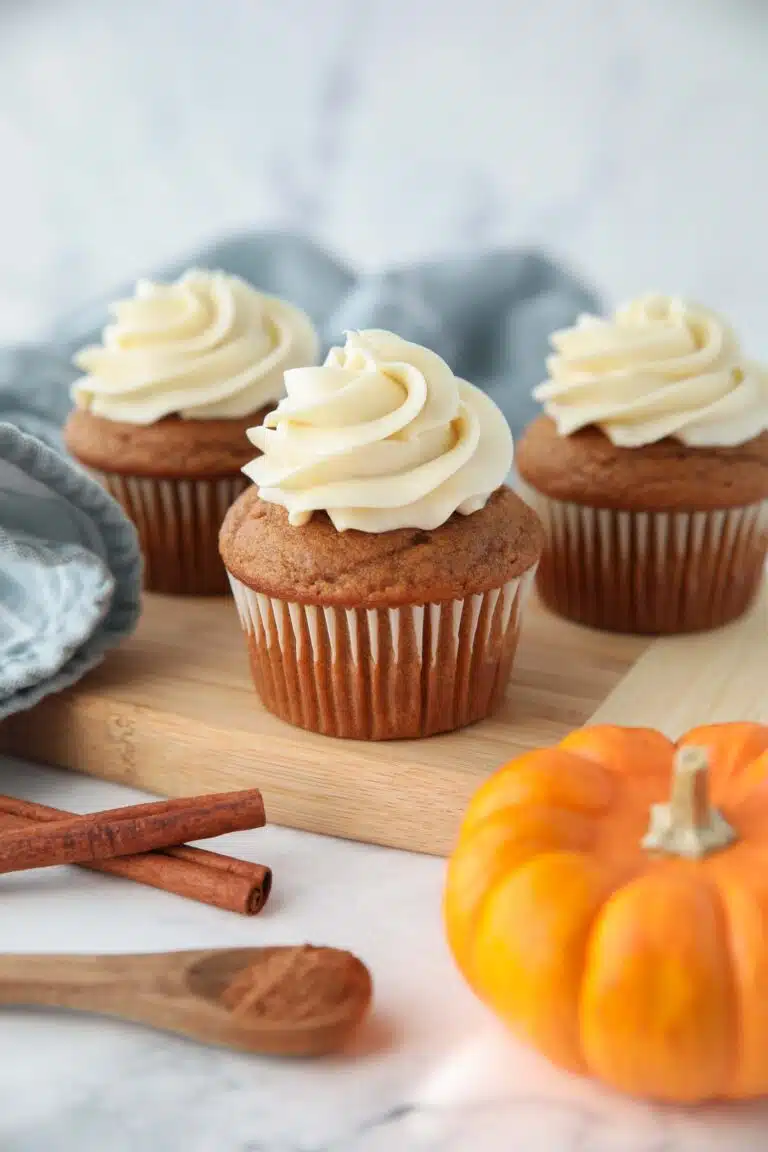 Side view of pumpkin cupcakes with cream cheese frosting piped on top.