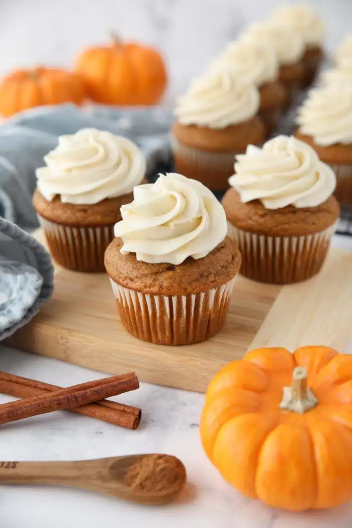 Pumpkin cupcakes with cream cheese frosting piped on top.