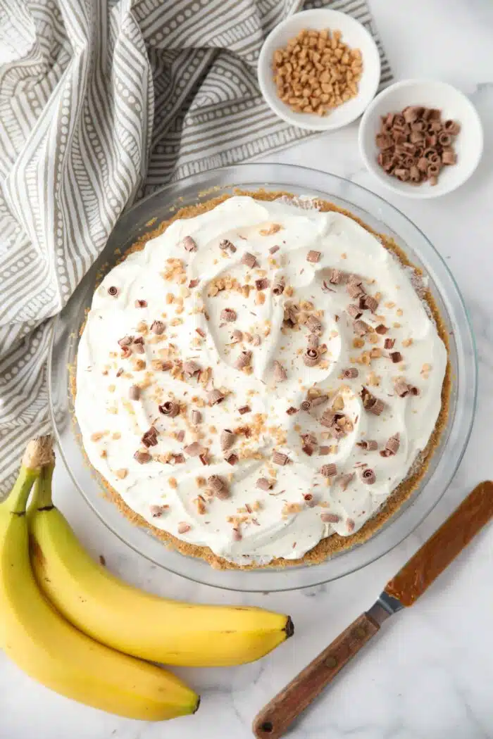 Top view of Banoffee Pie with whipped cream, toffee bits, and chocolate shavings.