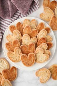 Top view of golden sugared palmiers on a plate.