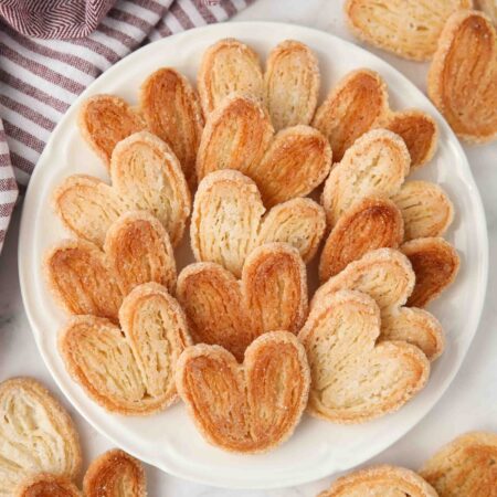 Top view of golden sugared palmiers on a plate.