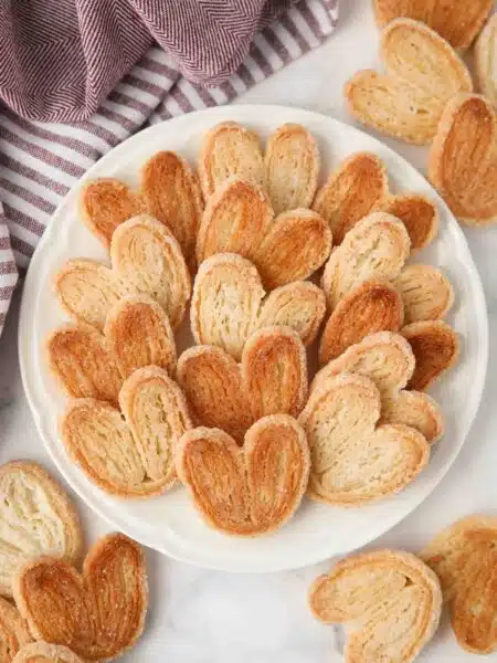Top view of golden sugared palmiers on a plate.