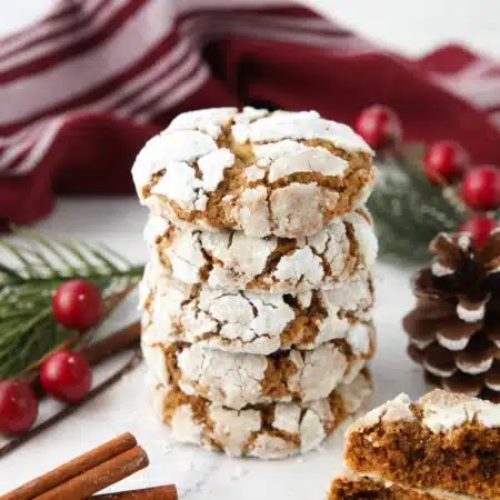 Stack of gingerbread crinkle cookies with powdered sugar cracks.