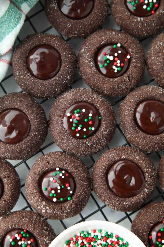 Close up of thumbprint chocolate cookies with ganache centers topped with holiday nonpareils.