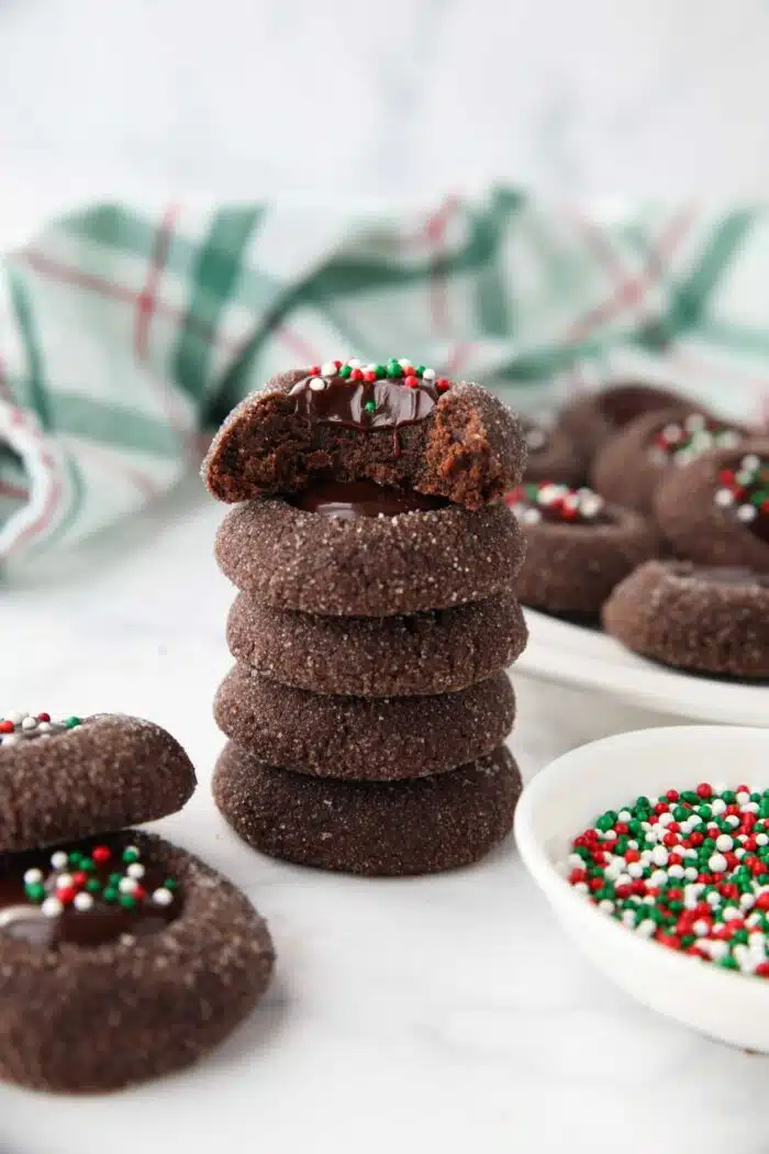 Stack of chocolate thumbprints with a bite taken out of the top one showing ganache center.