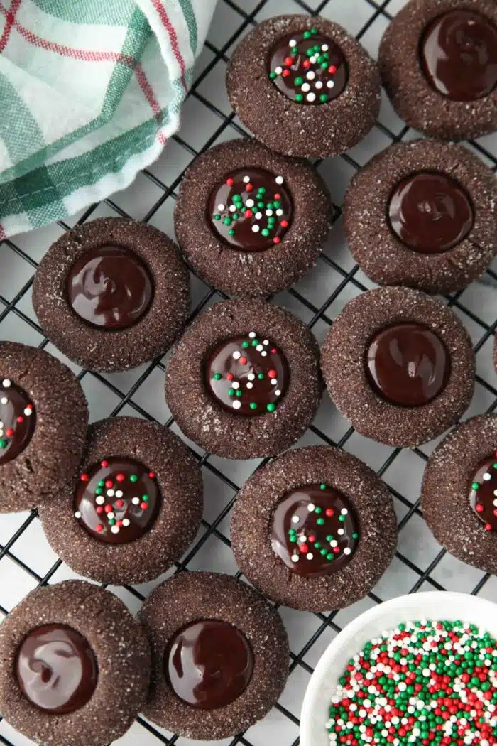 Mixture of chocolate thumbprint cookies on wire cooling rack. Some with sprinkles, some without.