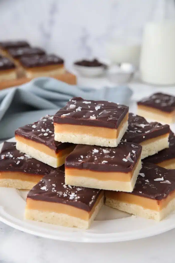 Plate full of caramel shortbread topped with chocolate and flaky salt.