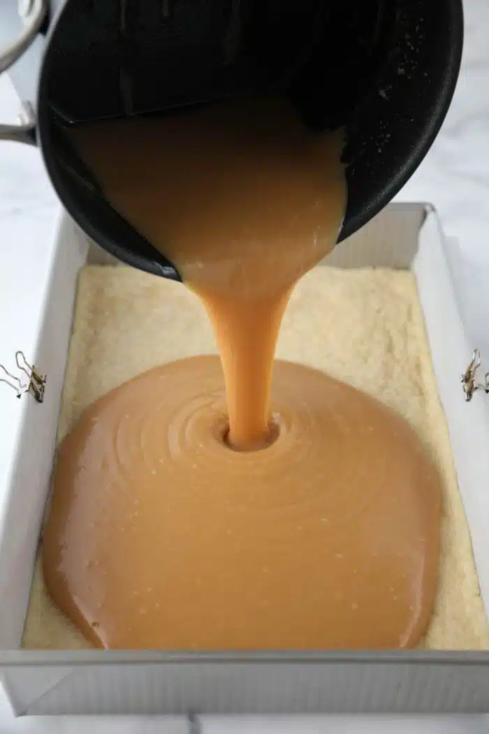 Pouring caramel over the shortbread crust.