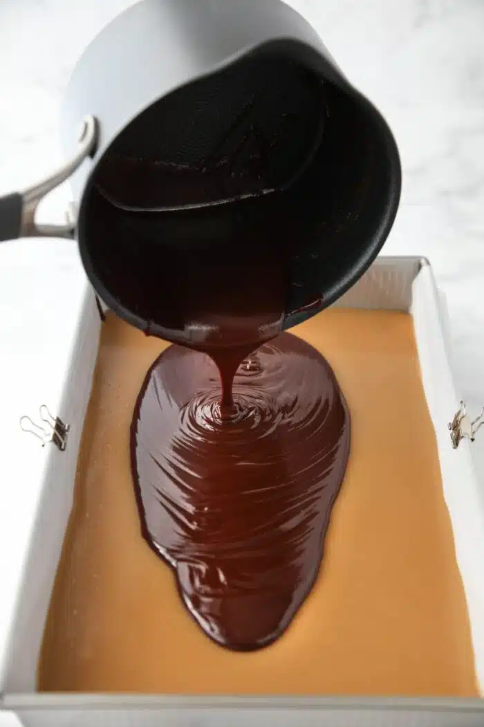 Pouring ganache over the caramel layer.
