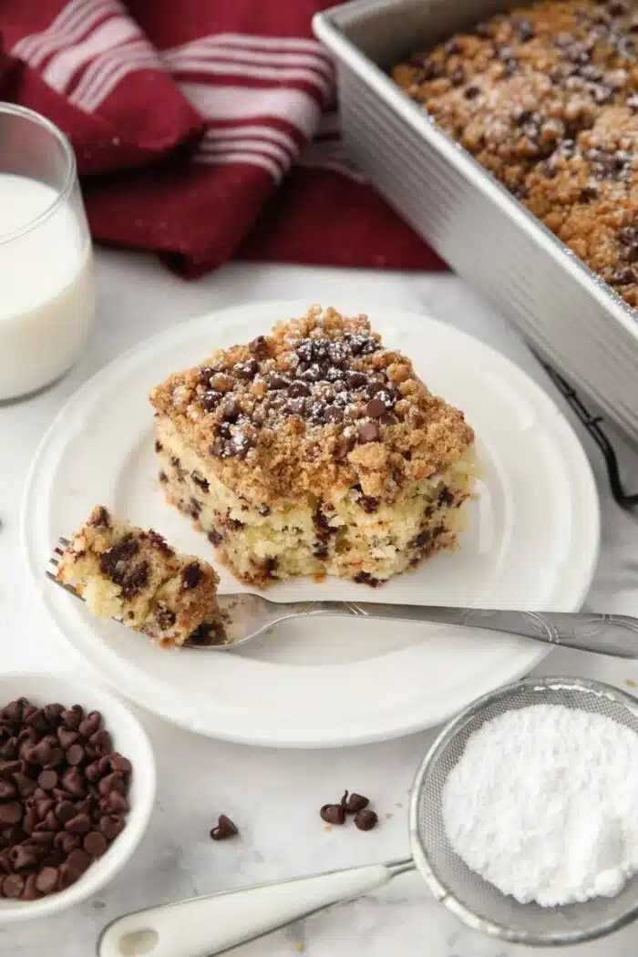 A forkful taken out of a slice of chocolate chip coffee cake on a plate.