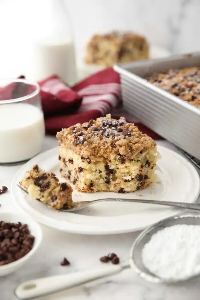 A forkful taken out of a slice of chocolate chip crumb cake on a plate.