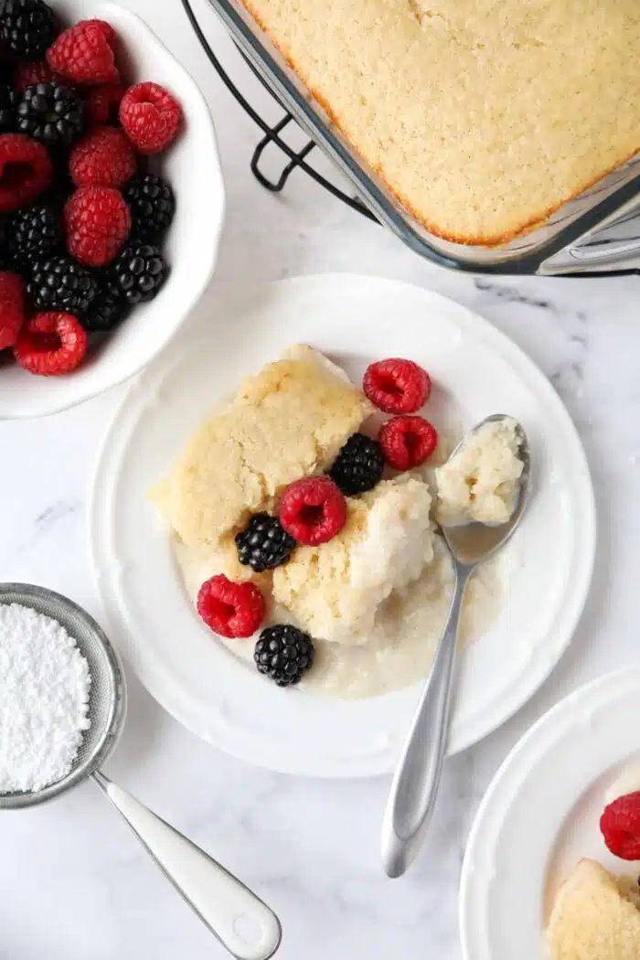 Top view of vanilla pudding cake on a plate with fresh berries.