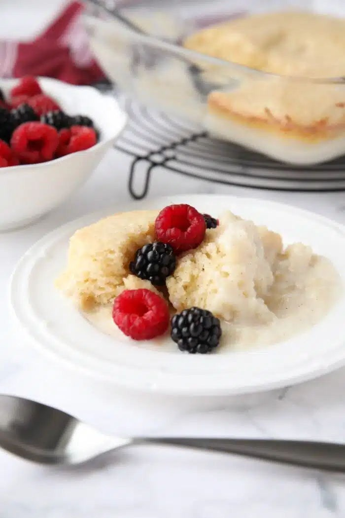 From scratch vanilla cake with vanilla pudding sauce on a plate with raspberries and blackberries.