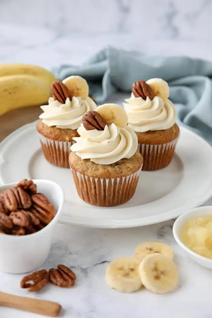 Banana pineapple pecan cupcakes on a plate with cream cheese frosting.