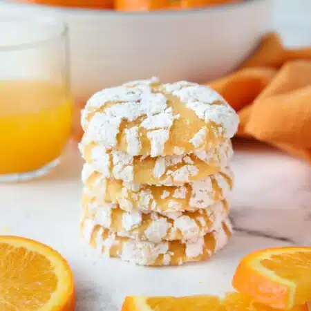 Stack of orange cookies with powdered sugar cracks.