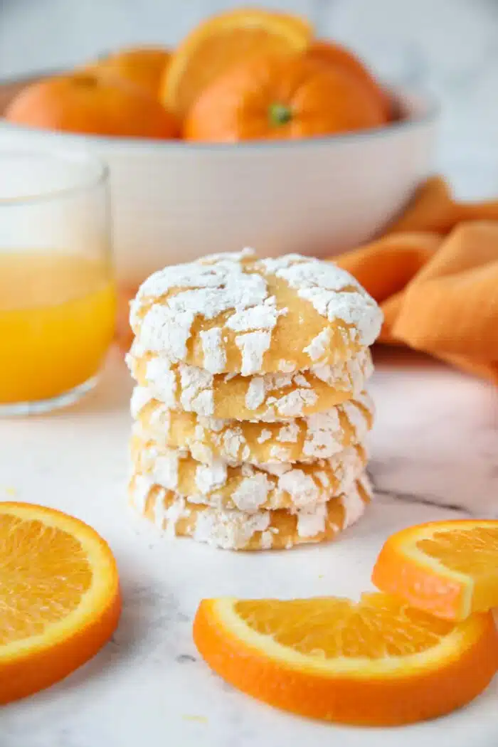 Stack of orange cookies with powdered sugar cracks.