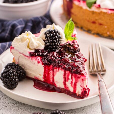 Slice of no bake blackberry cheesecake on a plate with a fork.