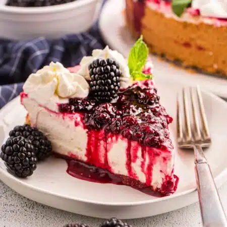Slice of no bake blackberry cheesecake on a plate with a fork.