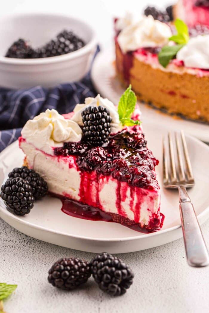 Slice of no bake blackberry cheesecake on a plate with a fork.