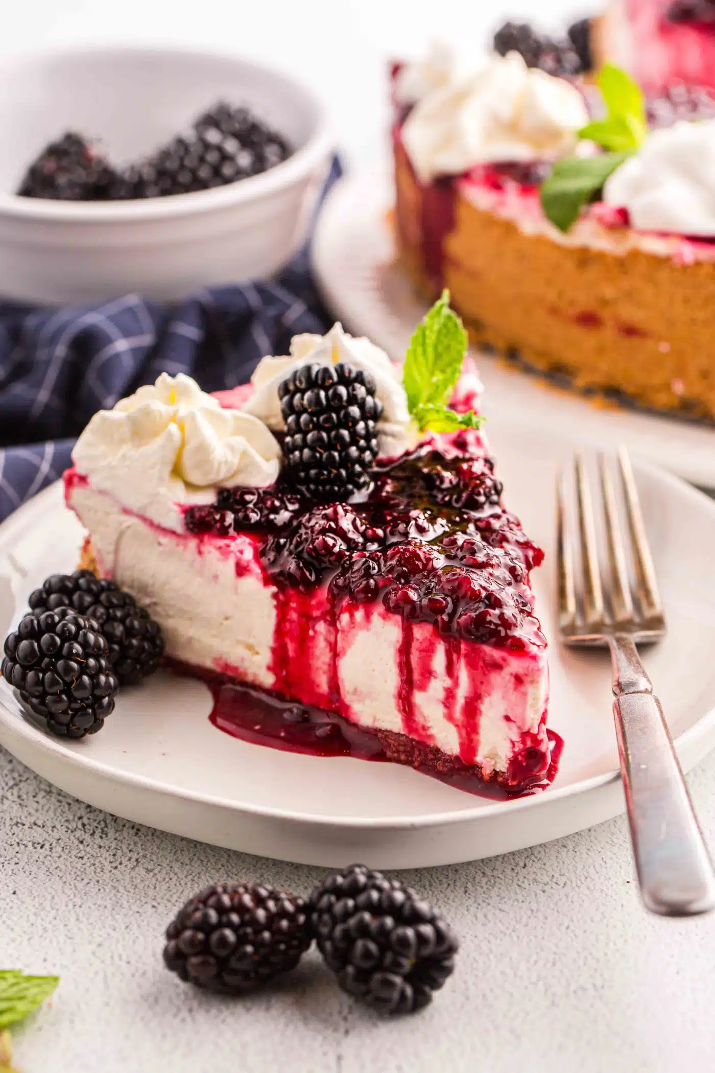 Slice of no bake blackberry cheesecake on a plate with a fork.