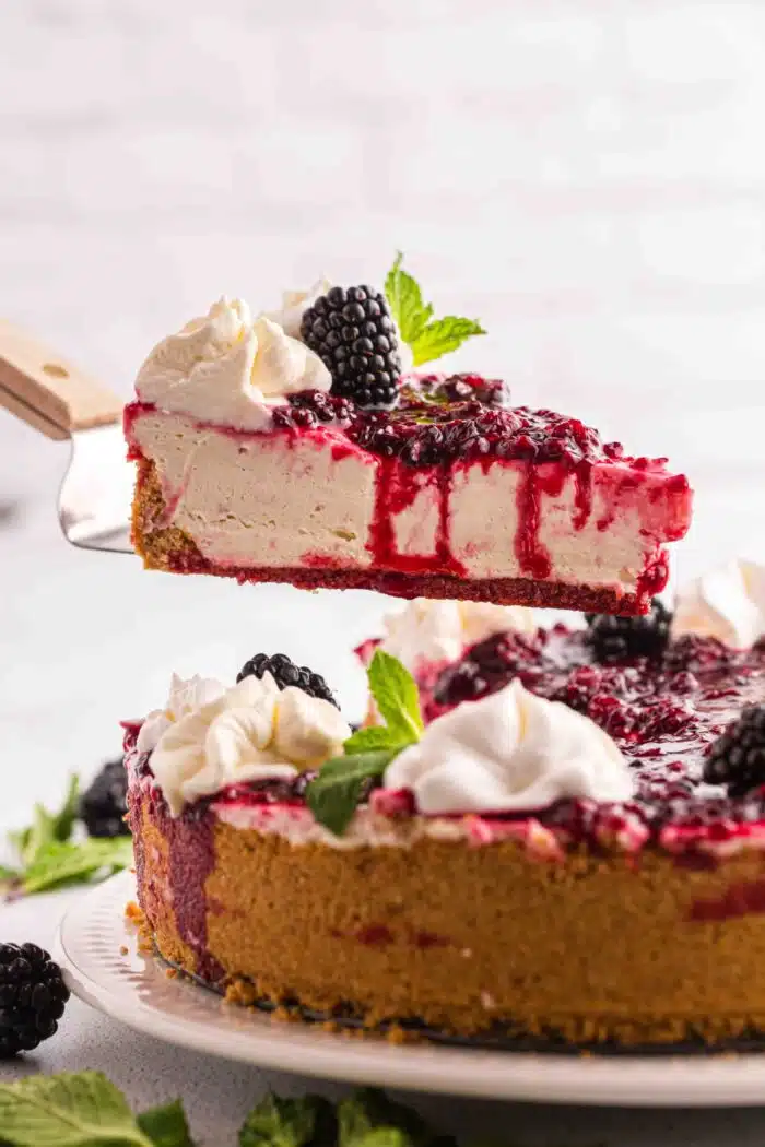 Lifting a slice of no bake berry cheesecake from the pan.