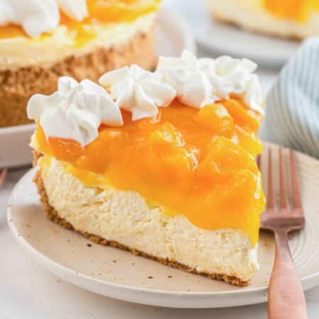 Slice of no bake peach cheesecake on a plate with a fork.