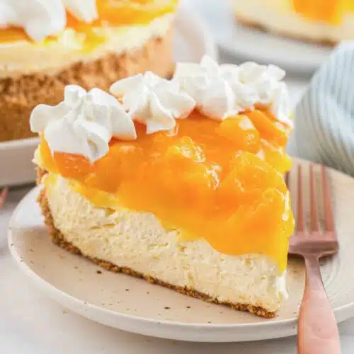 Slice of no bake peach cheesecake on a plate with a fork.