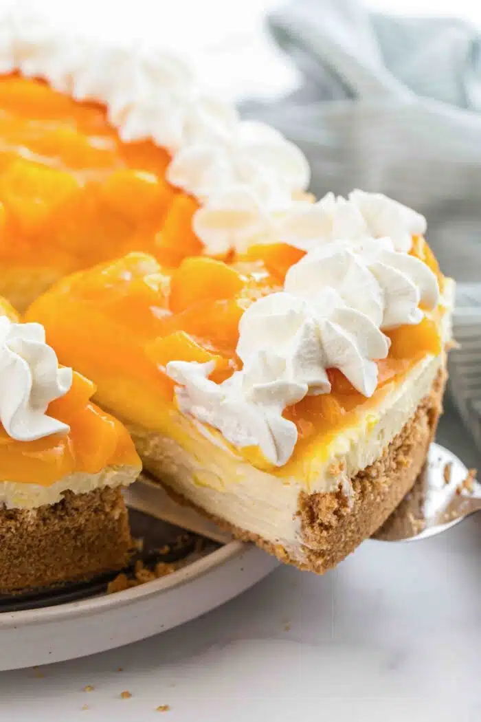 Lifting a slice of no bake peach cheesecake from the pan.