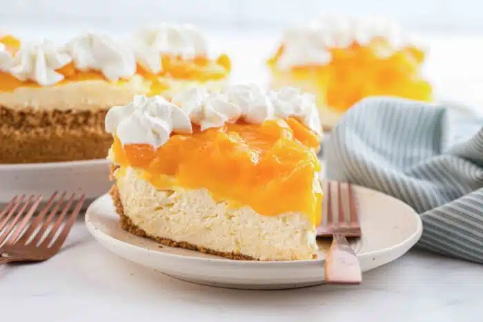 Slice of no bake peach cheesecake on a plate with a fork.