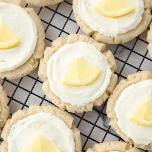 Close up of lemon sugar cookies with lemon frosting and a slice of lemon on top.