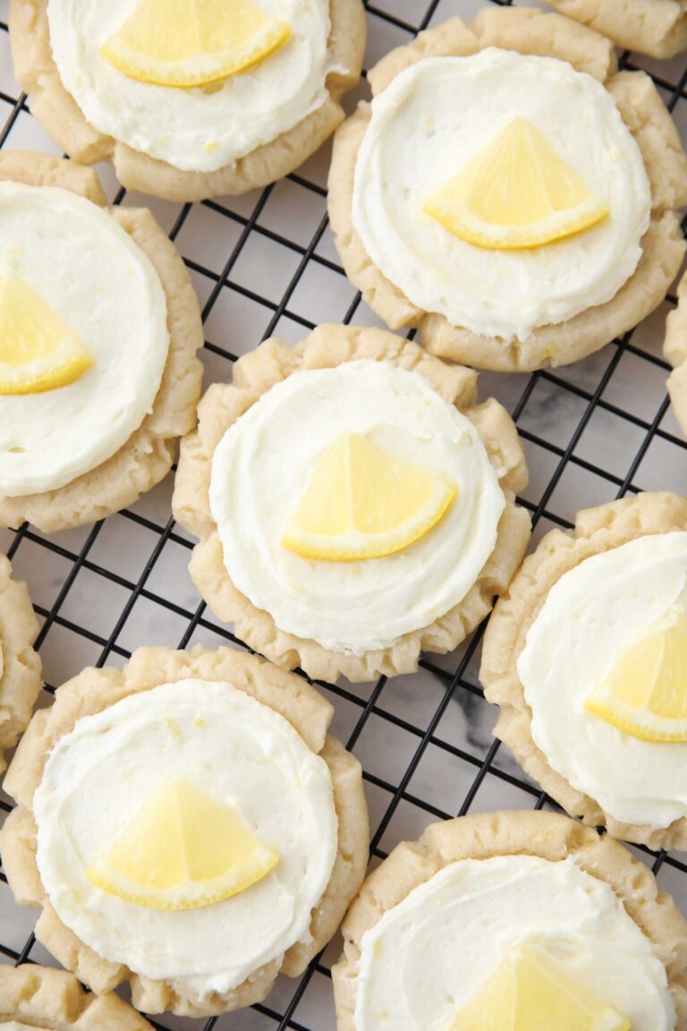 Close up of lemon sugar cookies with lemon frosting and a slice of lemon on top.