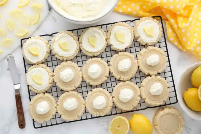 Topping lemon sugar cookies with lemon frosting and lemon slices.