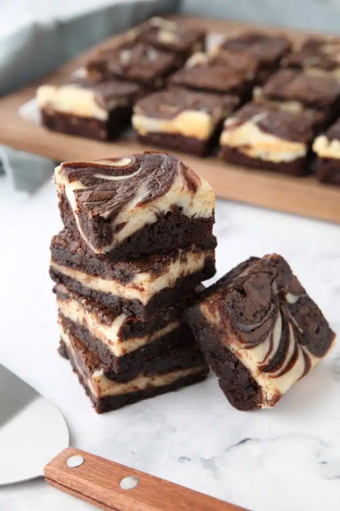 Stack of cream cheese brownies with swirls of brownie and cheesecake.