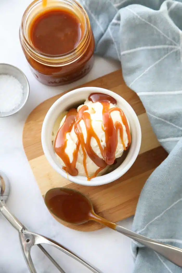 Homemade salted caramel sauce drizzled on top of ice cream in a bowl.