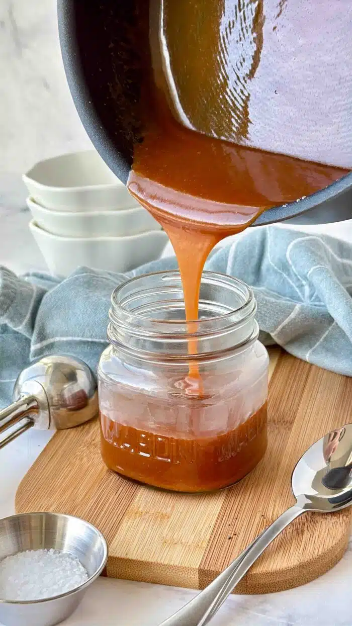 Pouring salted caramel sauce into a mason jar.
