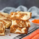 Carrot Cake Cheesecake Bars stacked on top of each other.